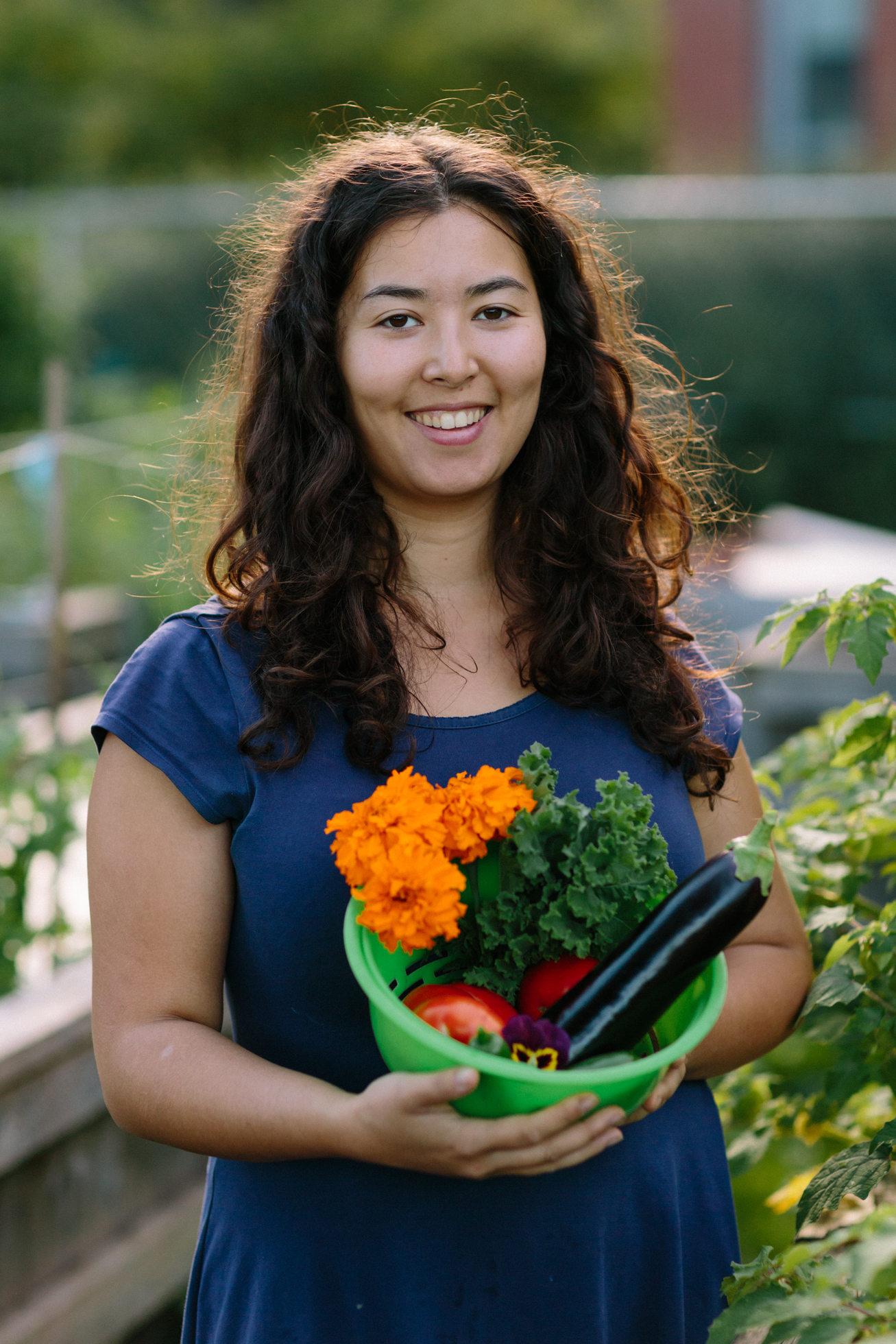 Kristen holding a basket of fresh-picked vegetables and flowers